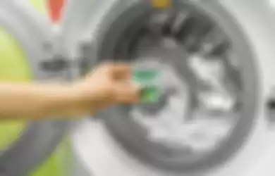 Ilustrasi menggunakan deterjen pada mesin cuci. 