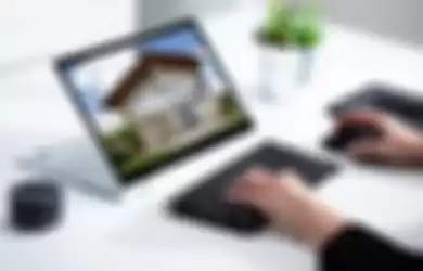Close-up of businesswoman's hand checking house on laptop
