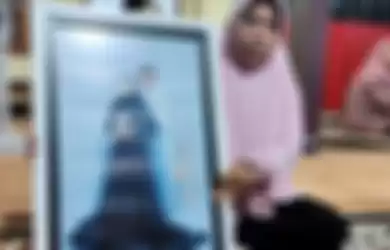 Yayak Dwi Ernawati, ibu mertua Serda Ede Pandu Yudha Kusuma, memegangi foto menantu dan anaknya saat ditemui di rumahnya di Banyuwangi, Kamis (22/4/2021) malam. Serda Ede Pandu Yudha Kusuma adalah awak Kapal Selam Nanggala yang hilang di perairan Bali, Rabu (21/4/2021). 