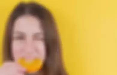 Ilustrasi wanita memakan buah jeruk.