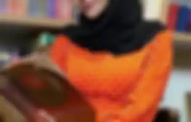 Aurel saat mengenakan long dress oranye bermotif polkadot yang dipadukan hijab hitam. Simpel dan cantik.