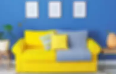 Paduan kuning pada sofa dan biru di dinding,berikan tampilan warna penuh semangat. 
