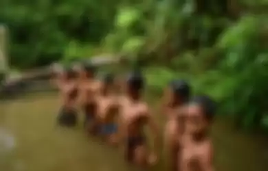 Anak-anak Suku Anak Dalam atau Orang Rimba bermain di sungai.  Orang Rimba menguburkan uang Rp 1,5 miliar di dalam tanah hutan gegara alasan ini. 