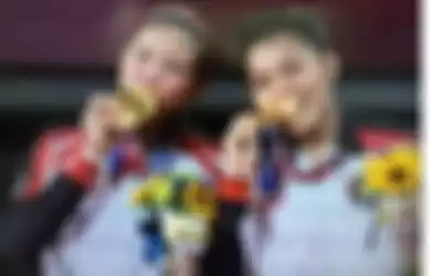 Greysia Polii dan Apriyani Rahayu menggigit medali emas seusai menang atas pasangan China dalam final bulu tangkis ganda putri Olimpiade Tokyo 2020.