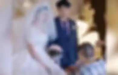 Seorang pria berlutut di hadapan mempelai wanita saat acara pernikahan.