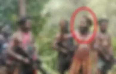 Tanpa mengenakan baju, Oni Kobagau berpidato dan didengarkan beberapa anggota KKB Papua yang menenteng senjata api. 