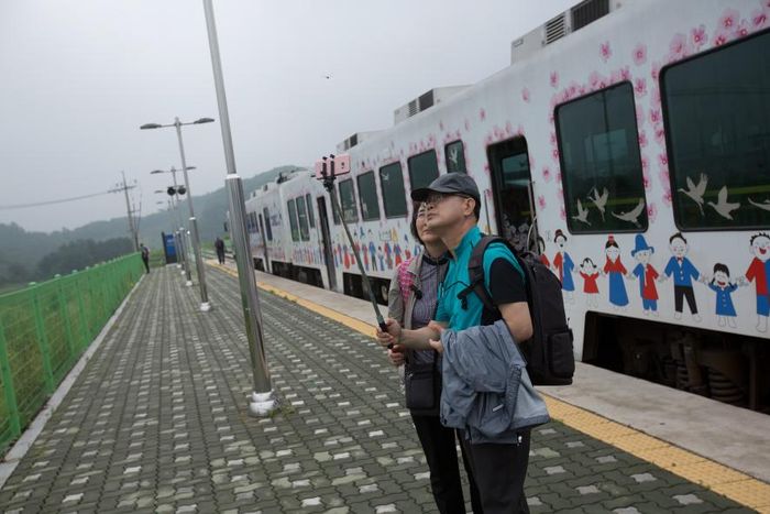 

National Geographic/David Guttenfelder
Wisatawan ber-selfie di depan DMZ Peace Train.