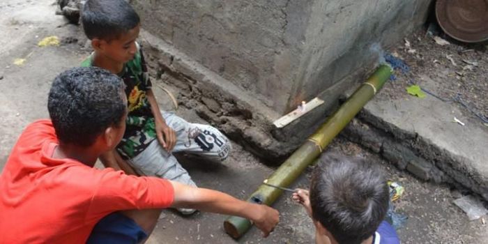 Tiga orang anak sekolah dasar di Kompleks Mabako, Kelurahan Watunggene, Kecamatan Kota Komba, Manggarai Timur, Flores, NTT, Jumat (19/12/2014) membunyikan meriam bambu