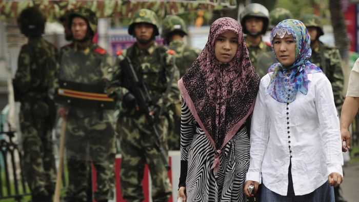 Two ethnic Uighur women pass Chinese paramilitary policemen standing guard outside the Grand Bazaar 