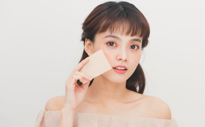 memakai blotting paper untuk menyerap minyak di wajah