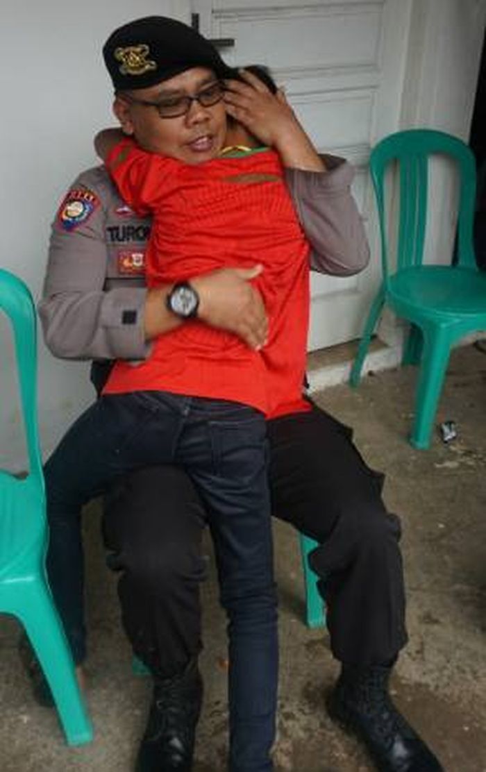 Pihak polisi menenangkan Aditia, calon pemain timnas U-13 Indonesia yang menjadi korban Tsunami Banten.