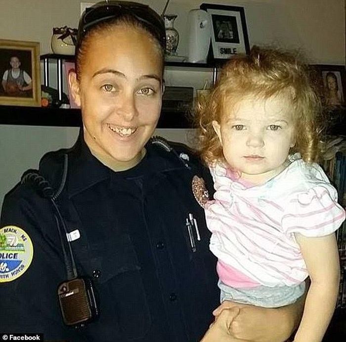 Cassie Baker (29) saat masih berseragam polwan tengah menggendong mendiang putrinya.