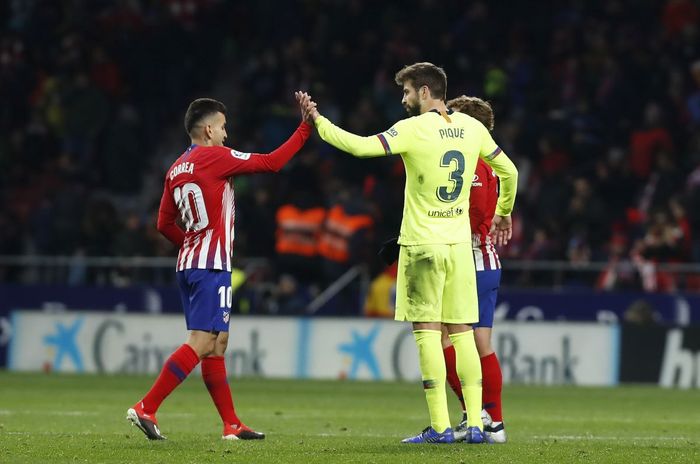 Bek Barcelona, Gerard Pique, memberikan salam kepada penyerang Atletico Madrid, Angle Correa, pada suatu laga Liga Spanyol.