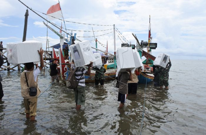 Petugas membawa logistik pemilu menyeberangi laut.