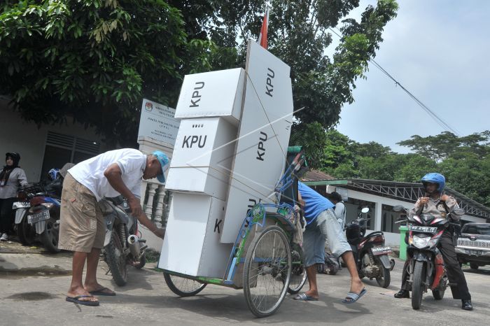 Petugas menyeberang sungai dan membawa logistik.