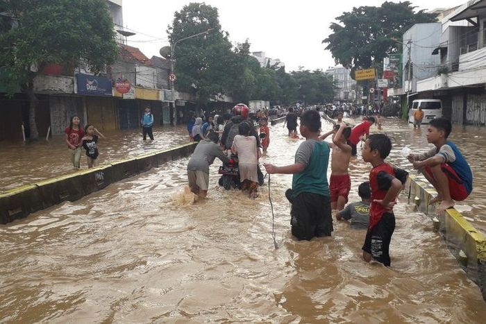 Petugas membersihkan saluran air yang tersumbat di Jalan Hasanudin setelah banjir kilat