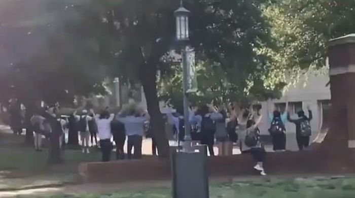 sebuah tangkapan layar video yang memperlihatkan sekelompok besar mahasiswa mengangkat tangan