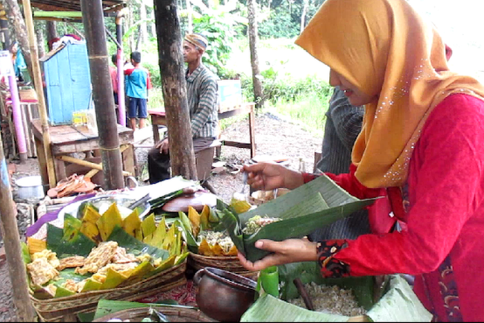 Pedagang membungkus makanan dengan daun pisang di Pasar Dhoplang Wonogiri.
