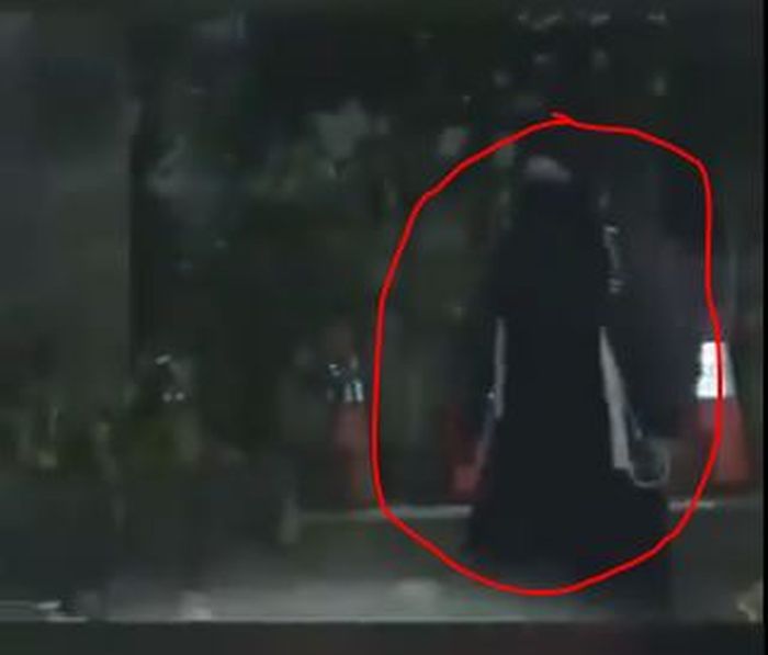 Sosok wanita berbaju hitam yang mendekati barisan polisi.