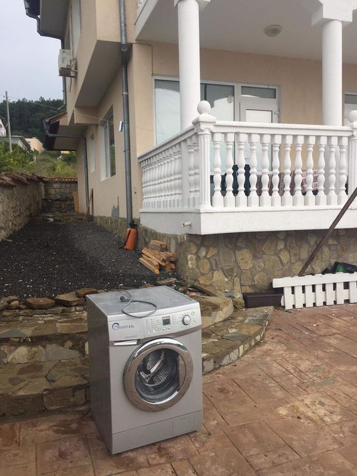 Mesin cuci rusak juga terlihat di depan rumah itu.
