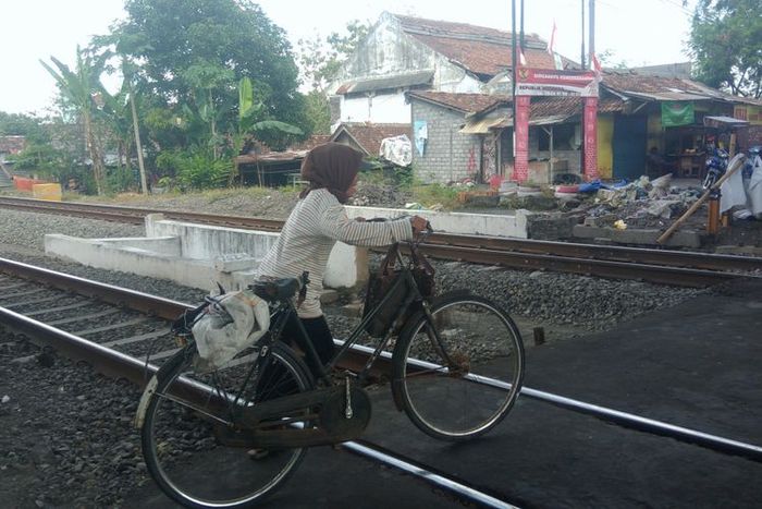 seorang Warga Menyebrang di jalur kereta api di bawah jembatan layang Janti