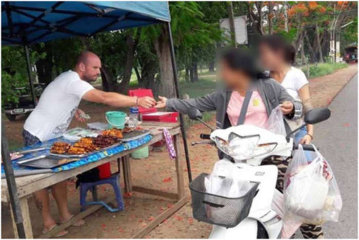 Pria bule yang membantu istrinya berjualan ayam bakar.