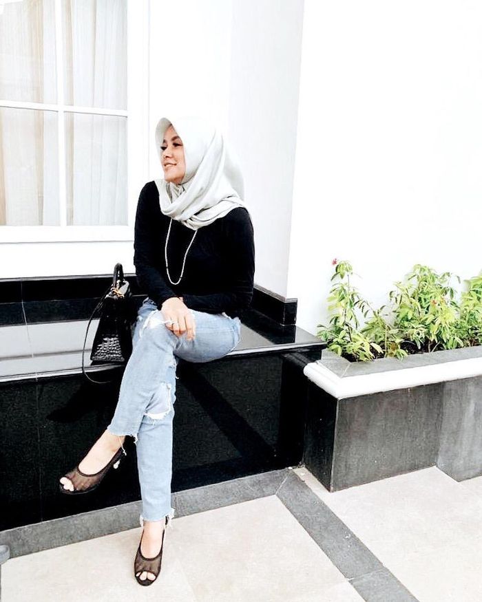 Olla Ramkan memadukan atasan hitam polos dengan celana ripped jeans