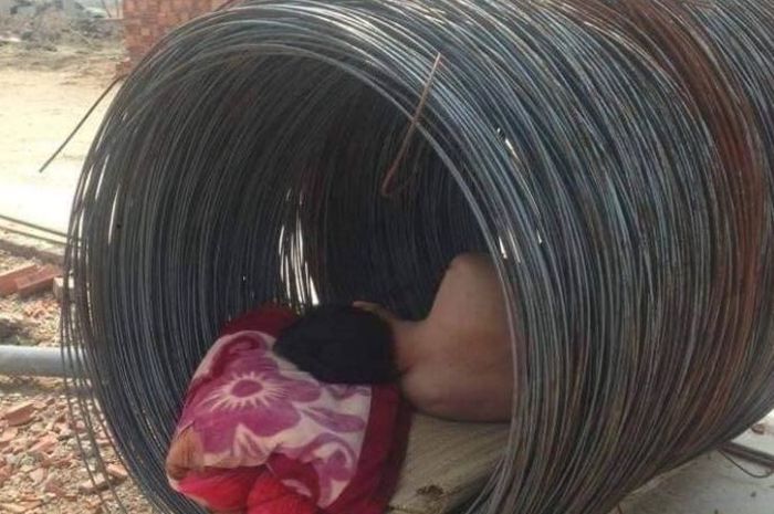Kuli bangunan tidur di dalam gulungan kawat.