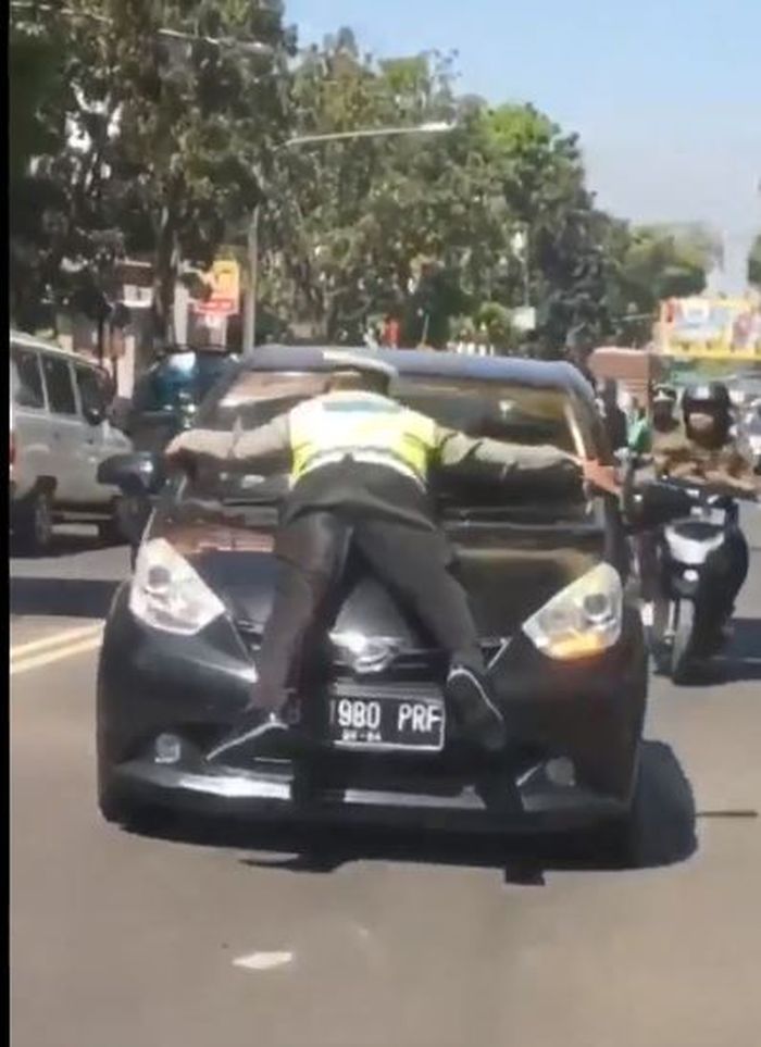 Polisi yang sampai bertahan di kap mobil sang pelanggar