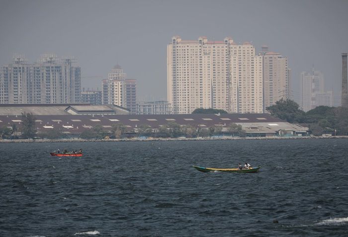 Pemandangan laut dengan latar belakang gedung bertingkat yang diselimuti asap polusi di Jakarta Utara, Rabu (31/7/2019). Berdasarkan data situs penyedia peta polusi daring harian kota-kota besar di dunia AirVisual, menempatkan Jakarta pada urutan pertama kota terpolusi sedunia pada Senin (29/7) pagi