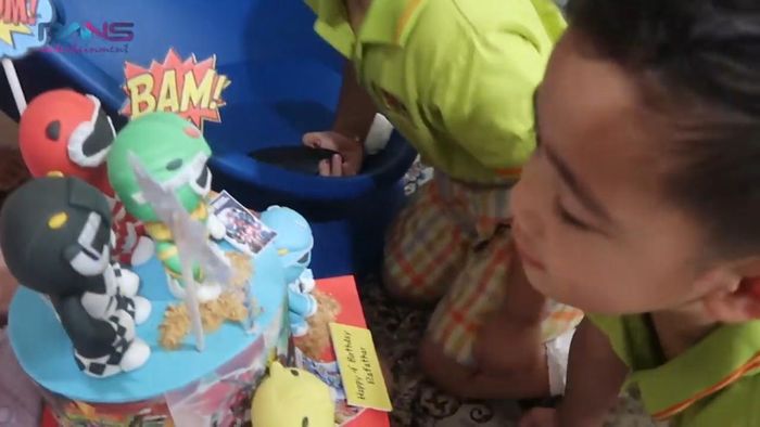 Rafathar meniup lilin dari kue Power Rangers-nya.