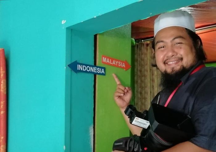 Osman Saide, saat berada di rumah dua negara dan menunjuk perbatasan yang dibuat oleh pemiliknya.