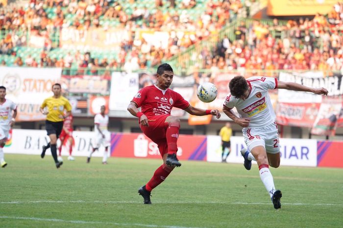 Penyerang Persija Jakarta berduel dengan salah seorang pemain Perseru Badak Lampung FC di Stadion Patriot Chandrabhaga, Kota Bekasi, Minggu (1/9/2019).