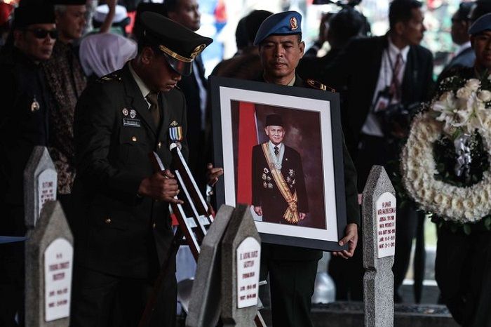 Personel Pasukan Pengamanan Presiden (Paspampres) membawa bingkai foto Presiden ke-3 Republik Indonesia, BJ Habibie menuju liang lahat saat tiba di Taman Makam Pahlawan Nasional Utama Kalibata, Jakarta Selatan, Kamis (12/9/2019). BJ Habibie meninggal dunia pada hari Rabu (11/9/2019) pukul 18.05 WIB