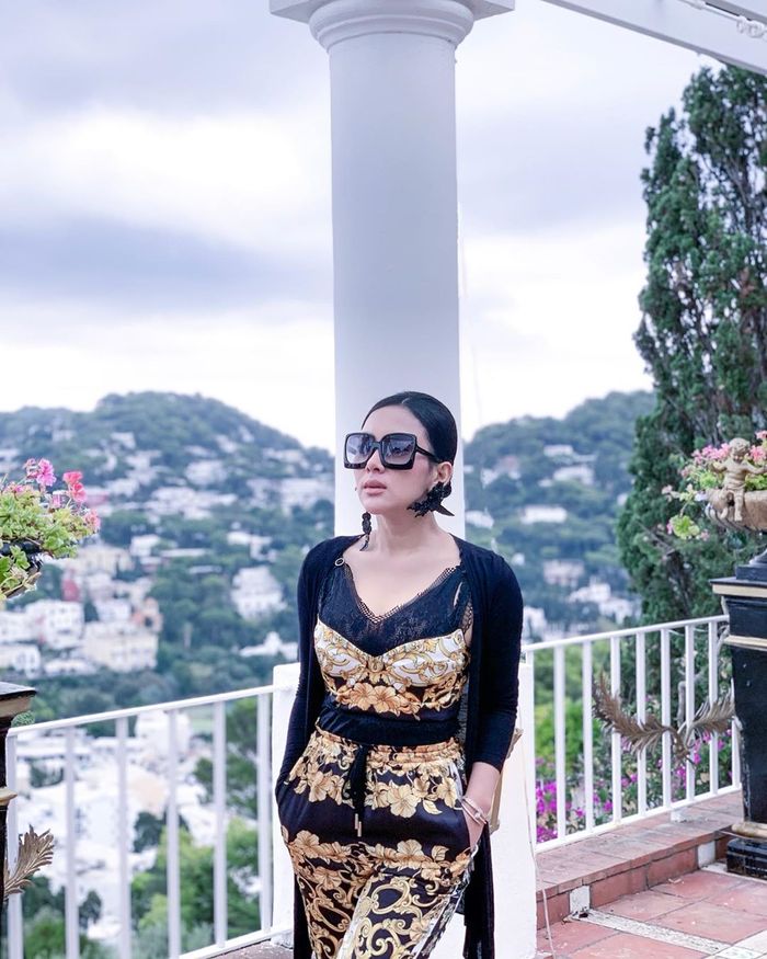 Syahrini tampil modis mengenakan atasan berupa bra motif bernuansa warna hitam dan gold