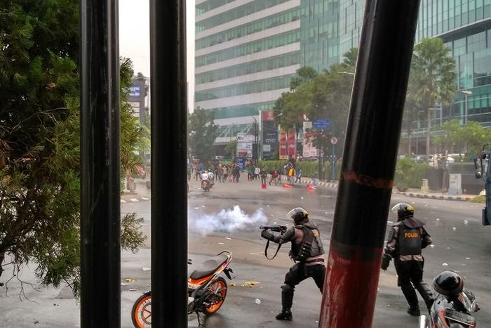 Seorang polisi menembakkan gas air mata ke arah massa aksi yang berhamburan setelah rusuh di depan gedung DPRD Sumut, Selasa (24/9/2019) sore.