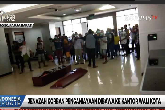 Keluarga dibantu warga sekitar bergotong royong menaruh peti berisi jenazah korban di loki kantor walikota.