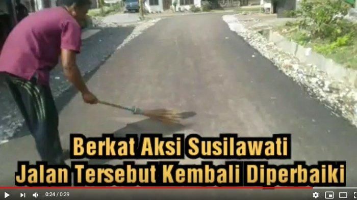 Tampak seorang ibu memperlihatkan kondisi aspal yang hanya digaruk rontok