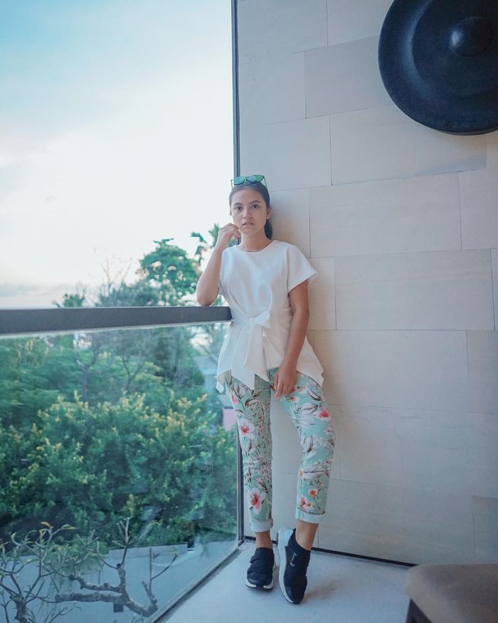  Marsha Aruan tampil mengenakan blouse berwarna putih model wrap dan celana motif floral