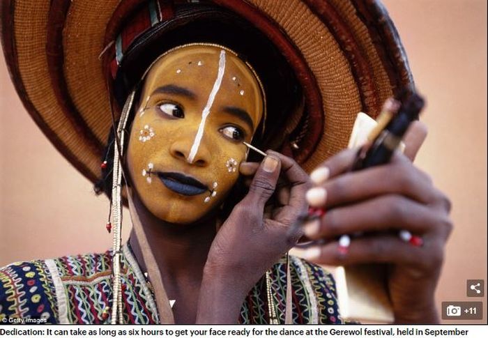 Seorang pria di suku Wodaabe sedang merias wajahnya.