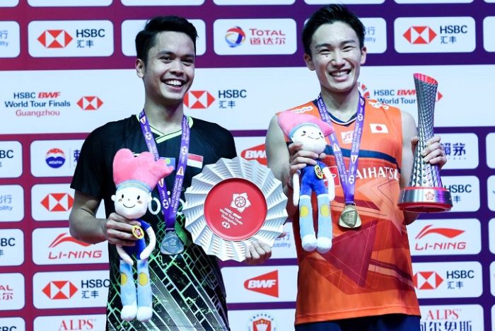 Pebulu tangkis tunggal putra Indonesia, Anthony Sinisuka Ginting (kiri), dan Kento Momota (kanan), berpose di atas podium juara BWF World Tour Finals 2019 di Tianhe Gymnasium, Guangzhou, China, Minggu (15/12/2019).