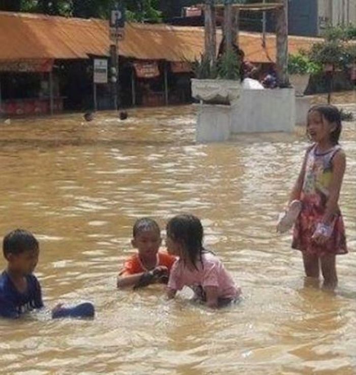 Anak-anak bermain di tengah banjir