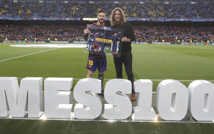 Kapten Barcelona, Lionel Messi, bersama mantan rekan sekaligus legenda El Barca, Carles Puyol, saat peringatan 100 gol Messi di ajang Liga Champions.