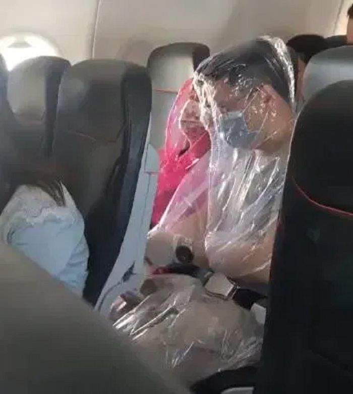 Sepasang penumpang telah terlihat menutupi seluruh tubuhnya menggunakan plastik untuk menghindari virus corona.