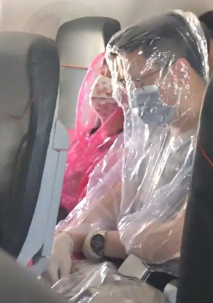 Sepasang penumpang telah terlihat menutupi seluruh tubuhnya menggunakan plastik untuk menghindari virus corona.
