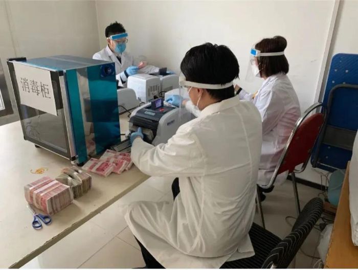 Para petugas pembasmi virus Corona dari permukaan uang kertas