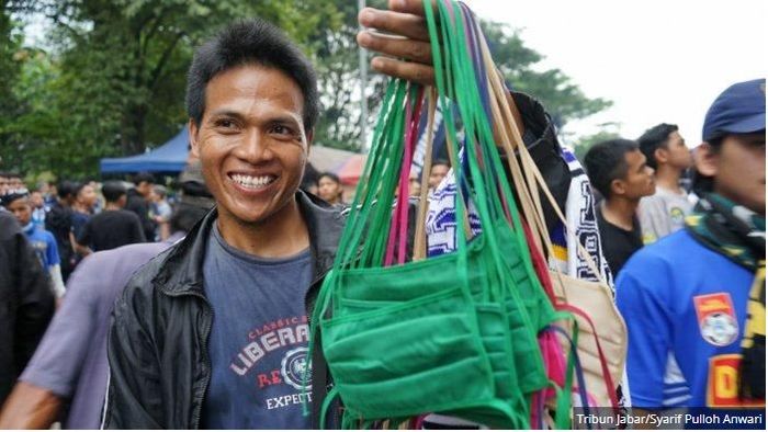 Ade Suryana, pedagang pernak-pernik Persib Bandung, kini juga berjualan masker di Stadion Si Jalak Harupat, Minggu (15/3/2020). 