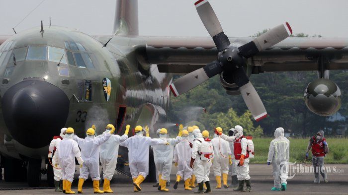 Penyemprotan cairan disinfekta kepada sejumlah petugas yang akan mengangkat alat kesehatan (alkes) dan obat yang dibawa dari Cina oleh Pesawat Hercules C-130 di Bandara Halim Perdana Kusuma, Jakarta Timur, Senin (23/3/2020).