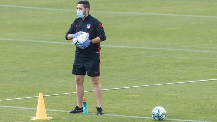 Salah satu pelatih Atletico Madrid membersihkan bola dengan disinfektan agra kelompok berikutnya yang akan berlatih bisa menggunakan bola yang bersih.