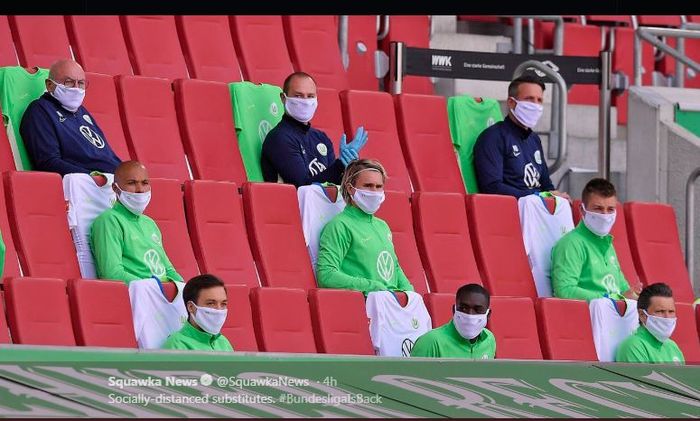 Para pemain cadangan dan anggota staf klub Wolfsburg duduk di tribune sembari menerapkan pembatasan jarak satu sama lain.